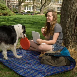 Student on the Quad with a dog and Frisbee